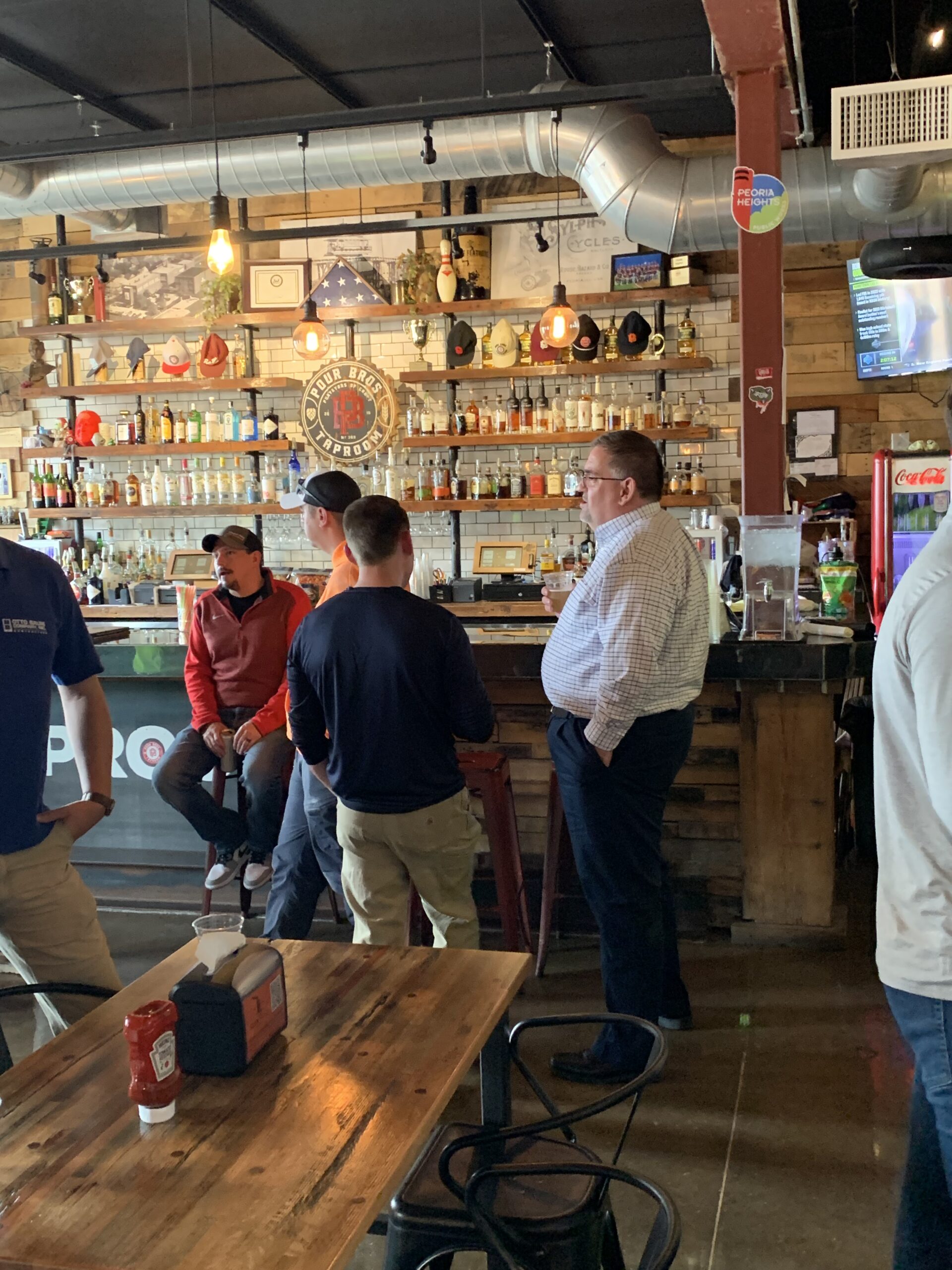 A group of people standing around in a bar.